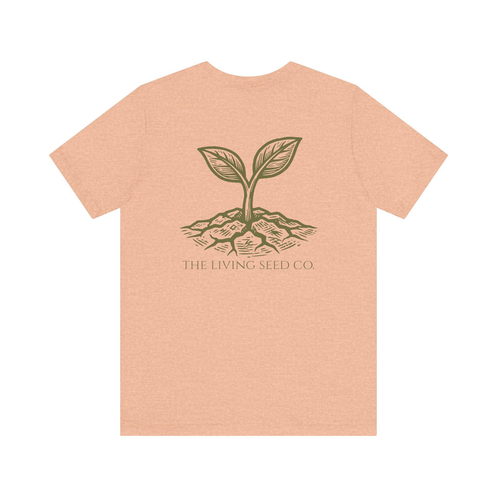 The Original Tee in Heather Peach — back view flat mockup — peach heather unisex t-shirt featuring The Living Seed Co. etching-style sprouting seed graphic in olive ink with wordmark below. Bella+Canvas 3001.