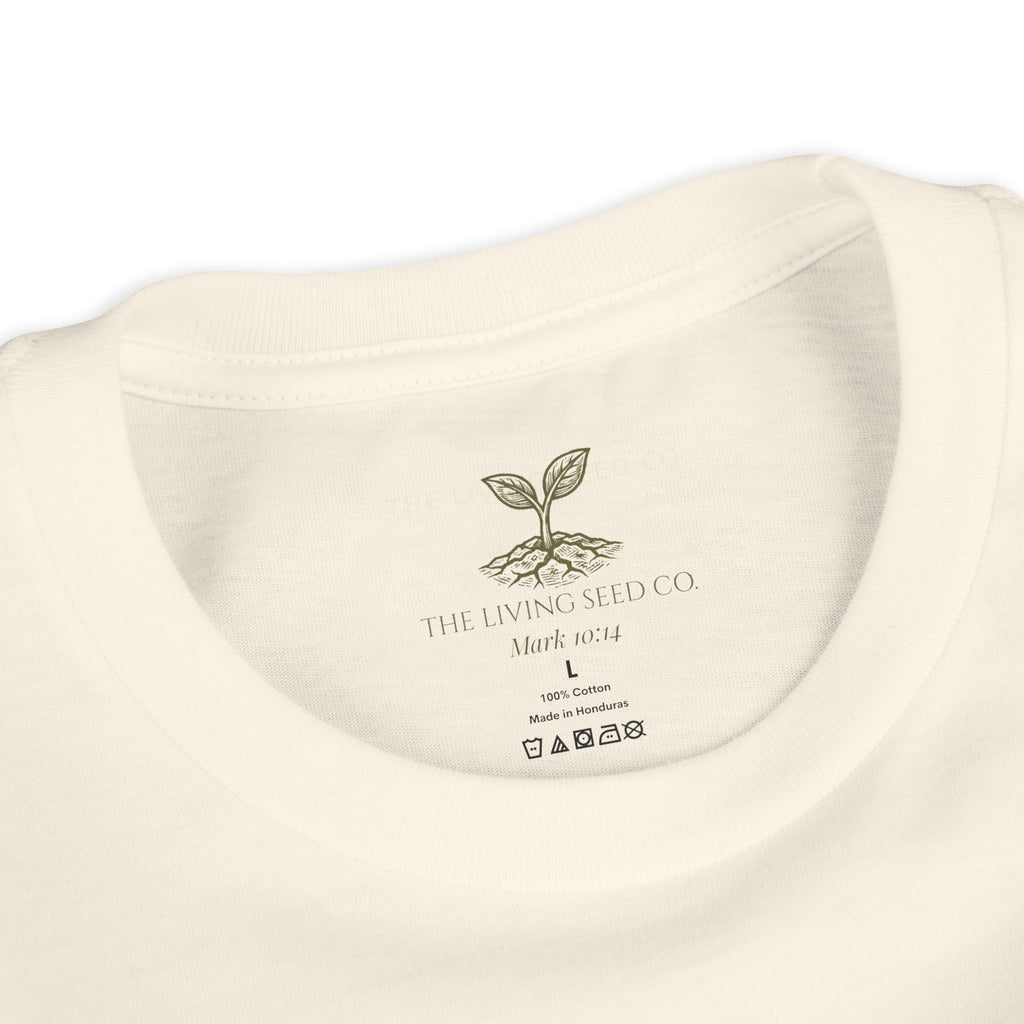 The Original Youth Tee in Natural — neck label closeup — custom printed label featuring The Living Seed Co. logo, Mark 10:14, size, fabric content, and care icons. 100% cotton, made in Honduras.