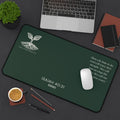 Scripture Series RENEWED Desk Mat in Forest Deep 12x22 — lifestyle shot — forest green desk mat on a dark workspace with laptop, coffee, and stationery featuring The Living Seed Co. seedling logo, Isaiah 40:31, RENEWED wordmark, and full Isaiah 40:31 verse in parchment ink.