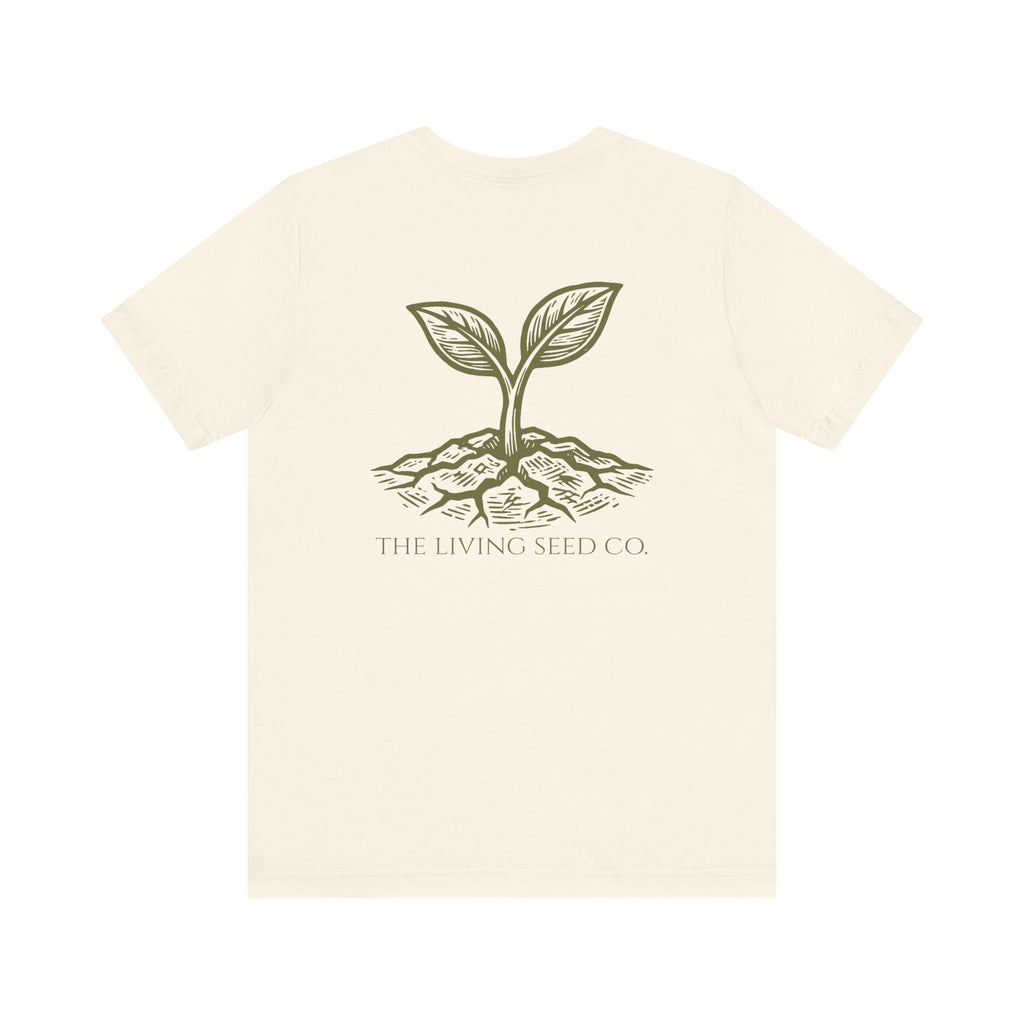The Original Tee in Natural — back view flat mockup — cream unisex t-shirt featuring The Living Seed Co. etching-style sprouting seed graphic in olive ink with wordmark below. Bella+Canvas 3001.