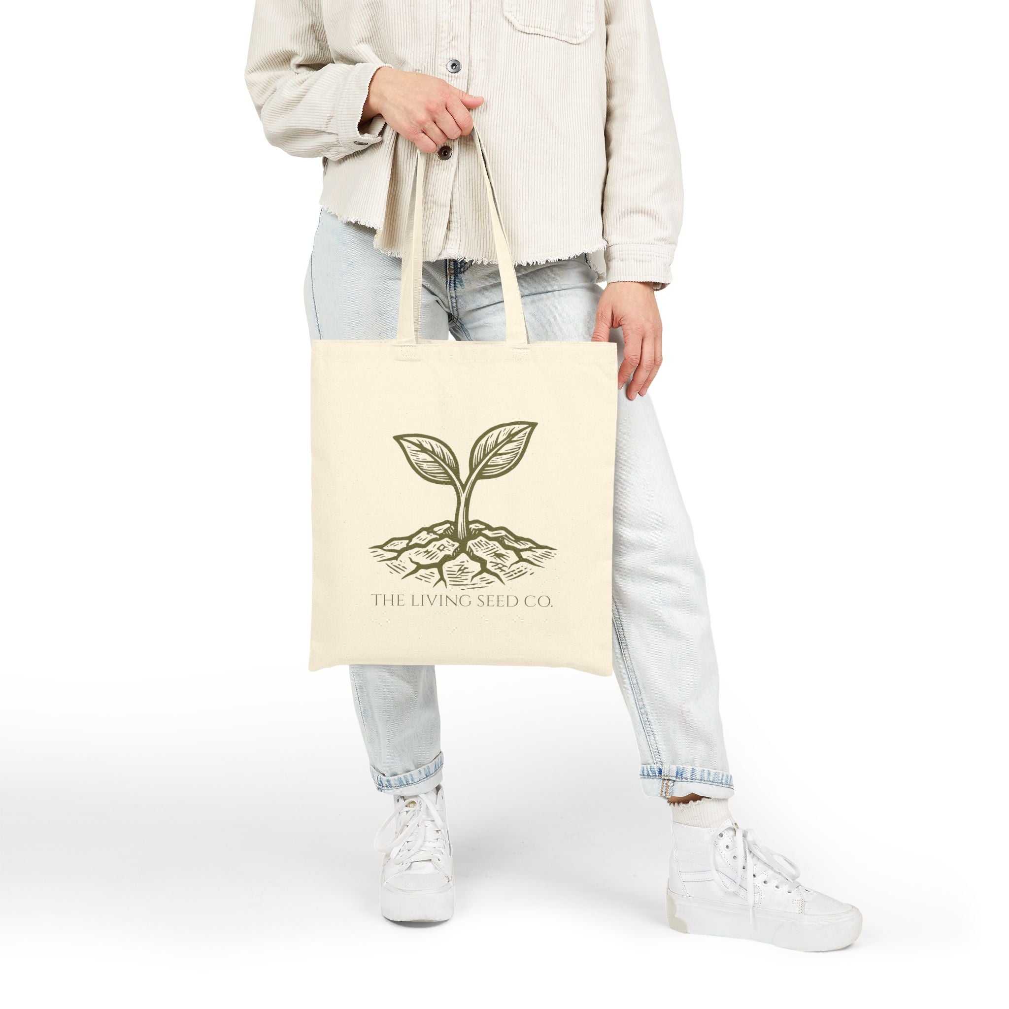 Person carrying The Original Canvas Tote in Natural, showing full size and 20-inch handles with etching-style sprouting seed graphic and The Living Seed Co. wordmark