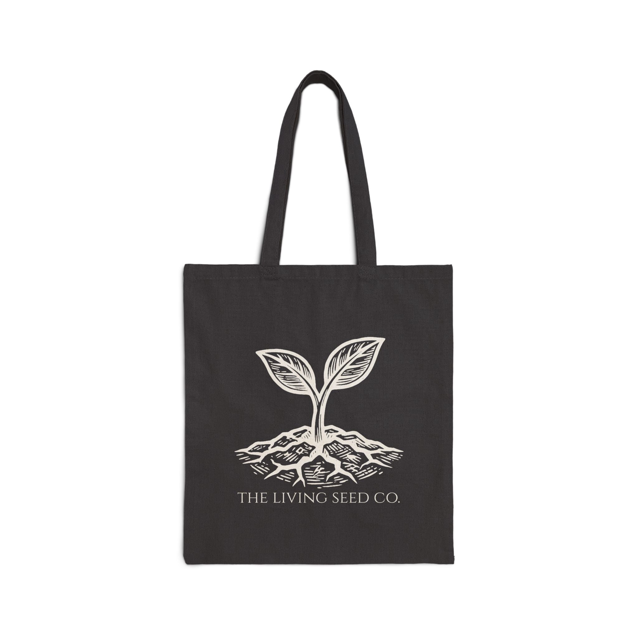 Flat product view of The Original Canvas Tote in Black showing etching-style sprouting seed graphic and The Living Seed Co. wordmark in parchment ink on 100% cotton canvas