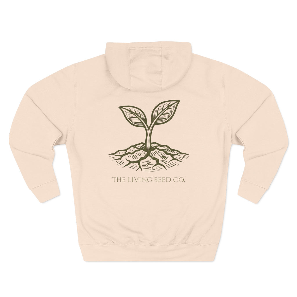 The Original Hoodie (Lane Seven) in Pale Pink — back view flat mockup — sandshell pullover hoodie featuring The Living Seed Co. etching-style sprouting seed graphic in olive ink with wordmark below. Lane Seven LS14001.