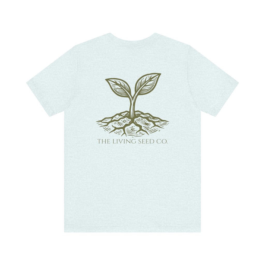 The Original Tee in Heather Ice Blue — back view flat mockup — light blue heather unisex t-shirt featuring The Living Seed Co. etching-style sprouting seed graphic in olive ink with wordmark below. Bella+Canvas 3001.