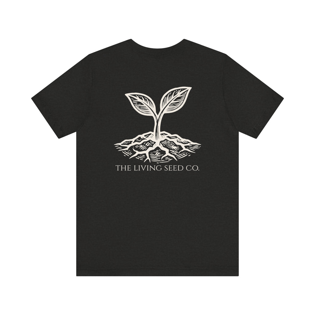 The Original Tee in Black Heather — back view flat mockup — dark grey unisex t-shirt featuring The Living Seed Co. etching-style sprouting seed graphic in parchment ink with wordmark below. Bella+Canvas 3001.