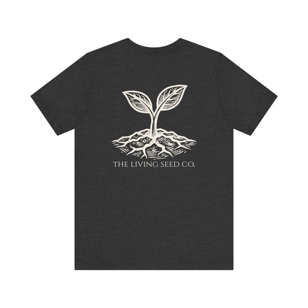 The Original Tee in Dark Heather — back view flat mockup — dark heather unisex t-shirt featuring The Living Seed Co. etching-style sprouting seed graphic in parchment ink with wordmark below. Bella+Canvas 3001.