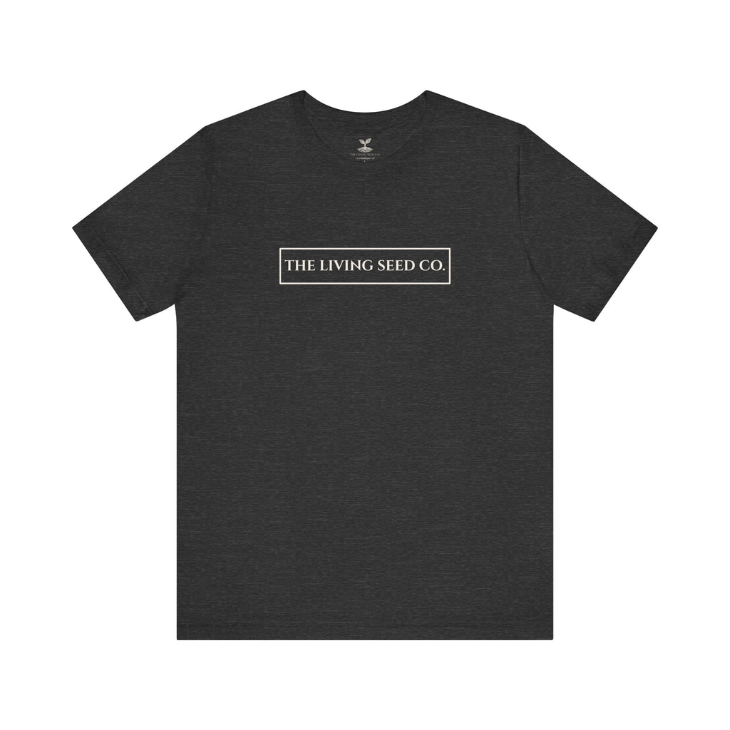 The Original Tee in Dark Heather — front view flat mockup — dark heather unisex t-shirt featuring The Living Seed Co. boxed wordmark on chest in parchment ink. Bella+Canvas 3001.